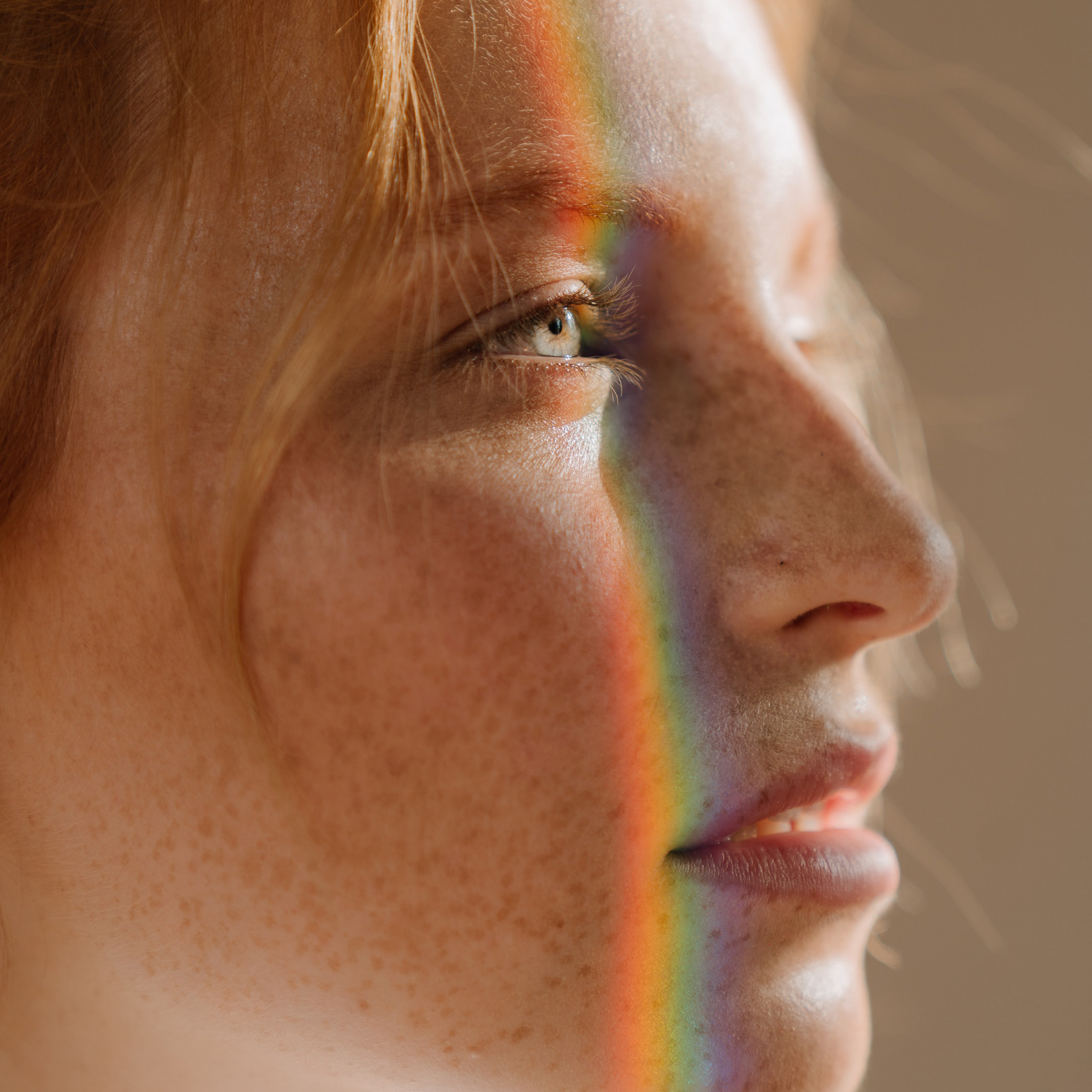 00_lichtfiltering_roodharige_vrouw_regenboog_weerspiegeling_op_gezicht_2048x2048